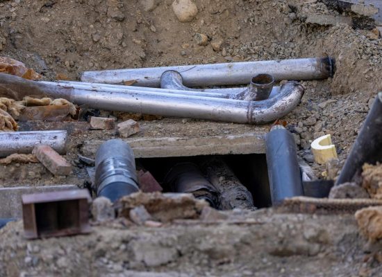 Close-up of urban pipe installation at a construction site, showing various pipes and materials.