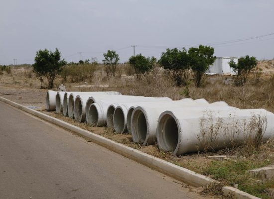 A row of concrete pipes on the roadside in a dry, rural setting.