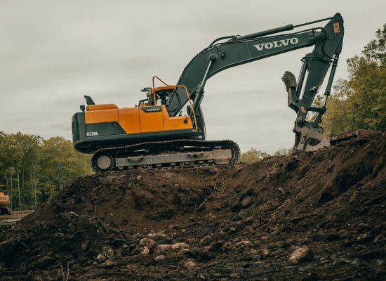 orange and white excavator on brown ground during daytime