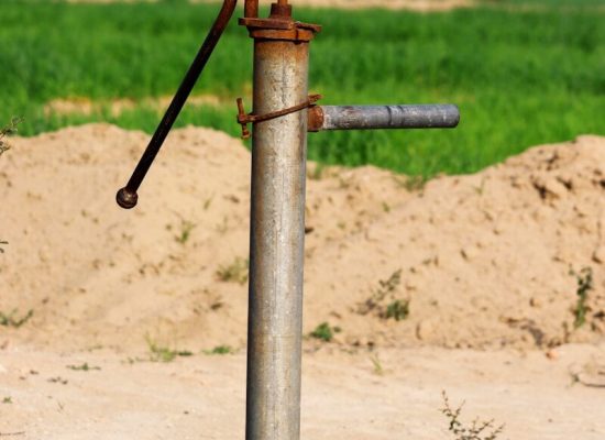 a pipe sticking out of the sand with a green field in the background